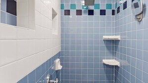Un bagno con piastrelle blu, un lavandino bianco, un portasciugamani e una piccola panca.