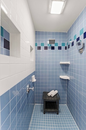 A bathroom with blue tiles, a white sink, a towel rack, and a small bench. - NEW! Retro Bungalow·Pool·Game Room·Walk to Beach (Cocoa Beach)