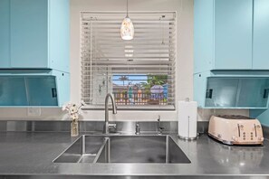 Open the window while you cook and let the Florida air in — the surfboards outside are a reminder of exactly where you are. - NEW! Heated Pool·Retro Bungalow·Game Room·Walk to Beach (Cocoa Beach)