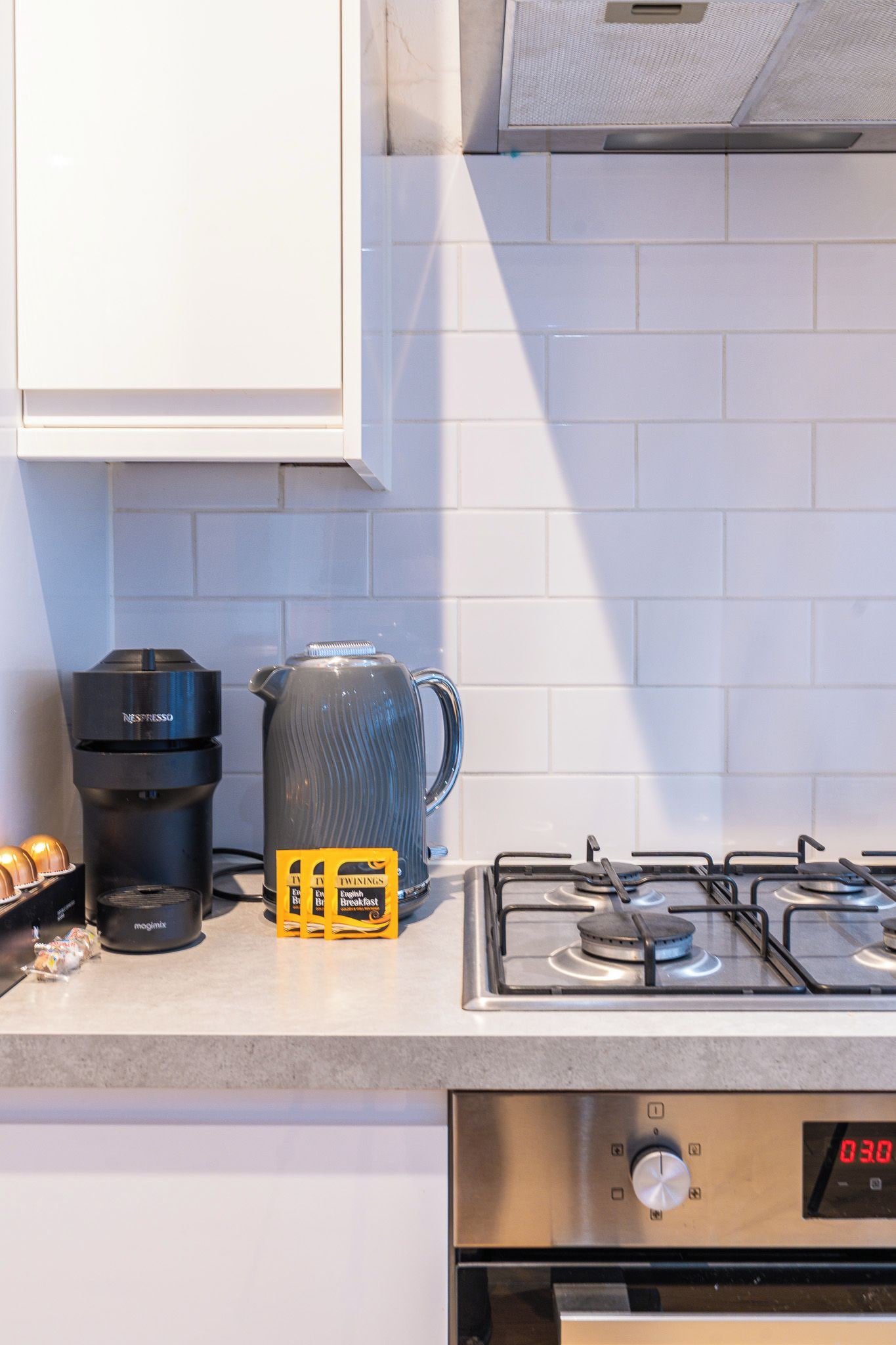 Een keuken met een koffiezetapparaat, een waterkoker en een fornuis.