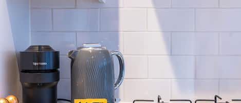 A kitchen with a coffee maker, a kettle, and a stove.