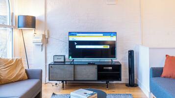 A modern living room with a flat-screen TV, grey sofa, coffee table, and a grey rug.