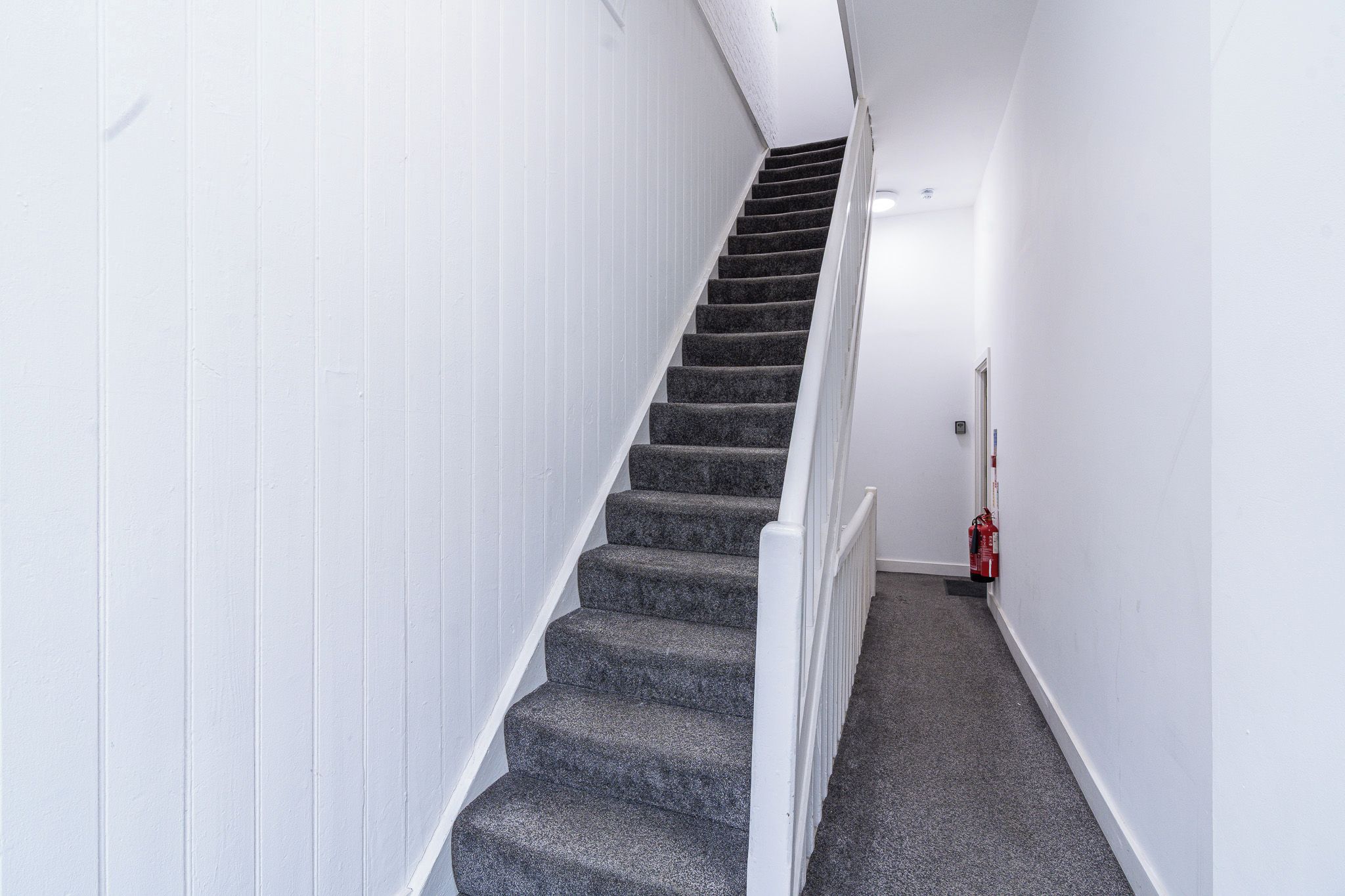 Een trap met witte muren en beklede treden.