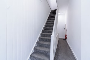 A staircase with white walls and carpeted steps.