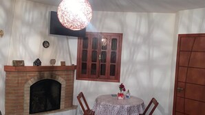 Quarto com lareira, mesa de jantar com cadeiras, armário de madeira e uma porta.