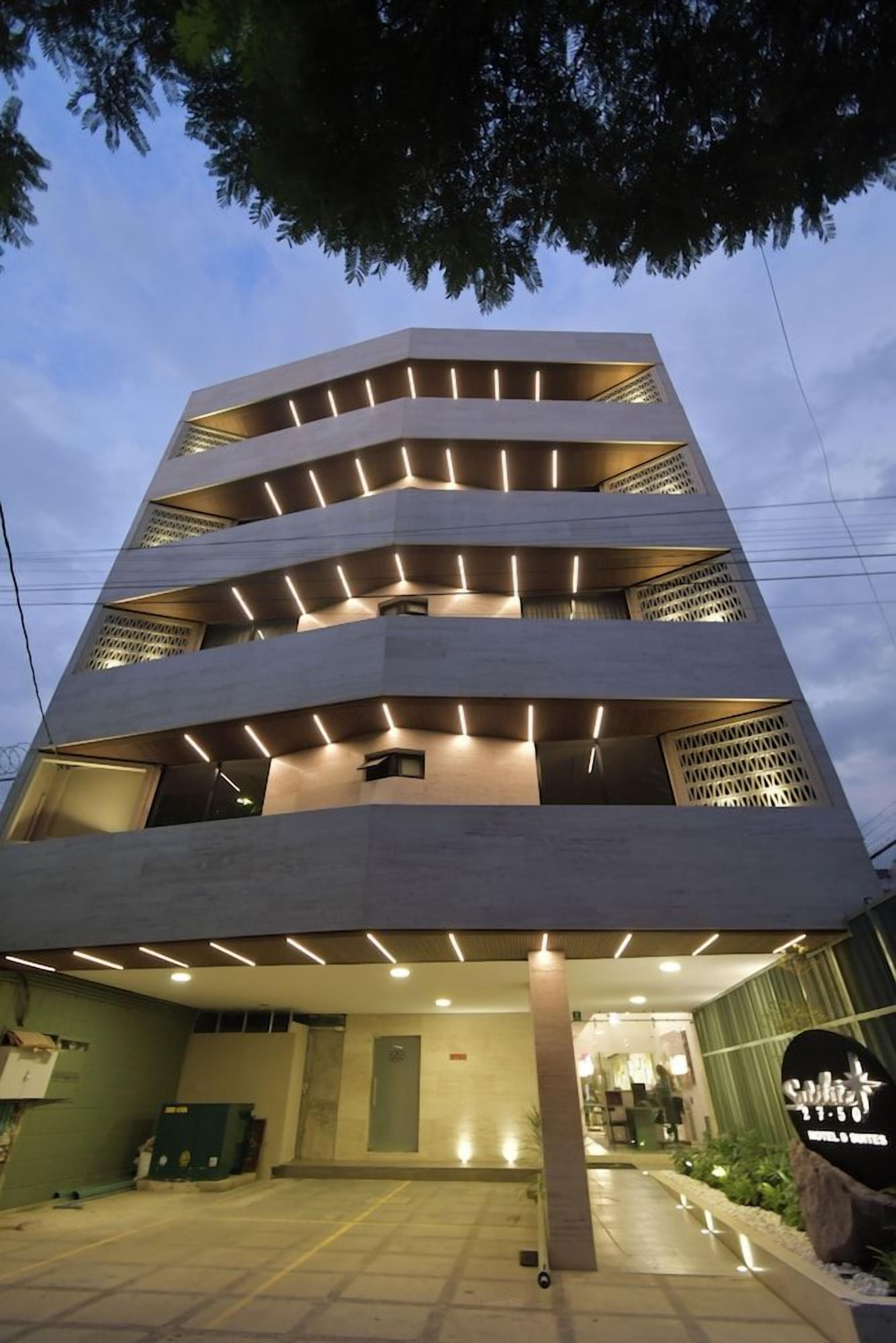 A multi-story hotel with a modern design, featuring a central courtyard and a sign indicating it is a hotel.