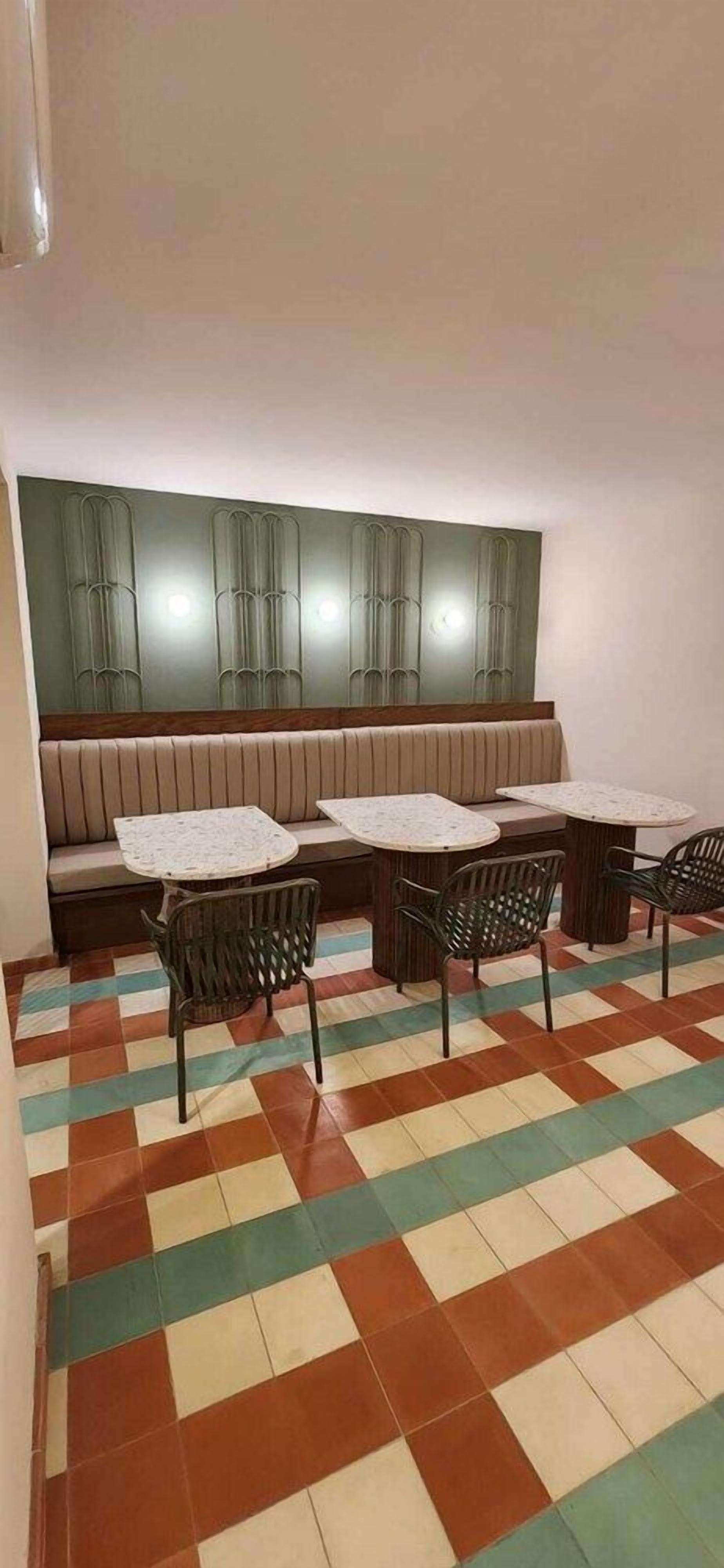 A seating area with a bench and tables, a patterned floor, and a wall with cabinets.
