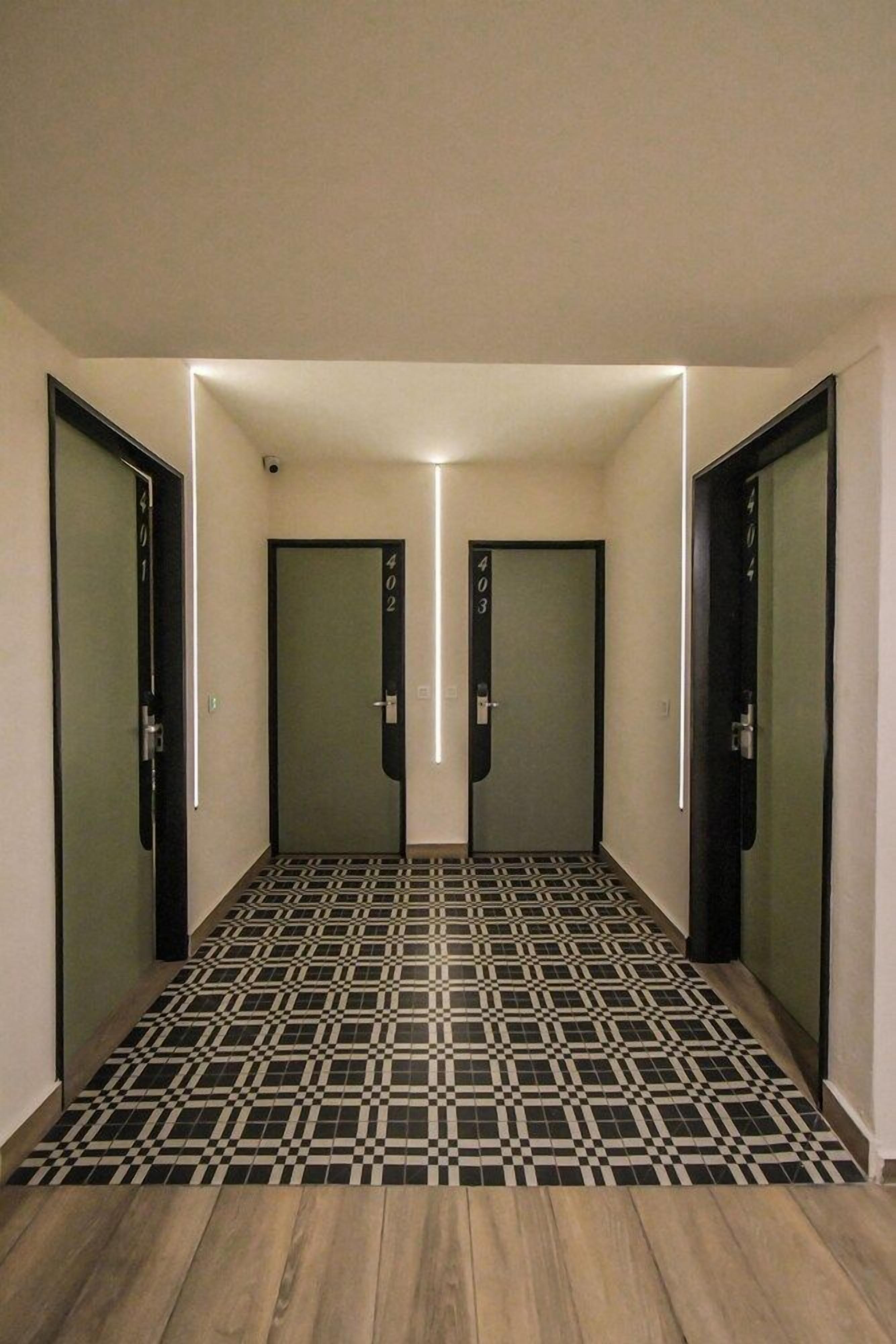 Un pasillo con puertas espejadas, piso estampado y una lámpara en el techo.