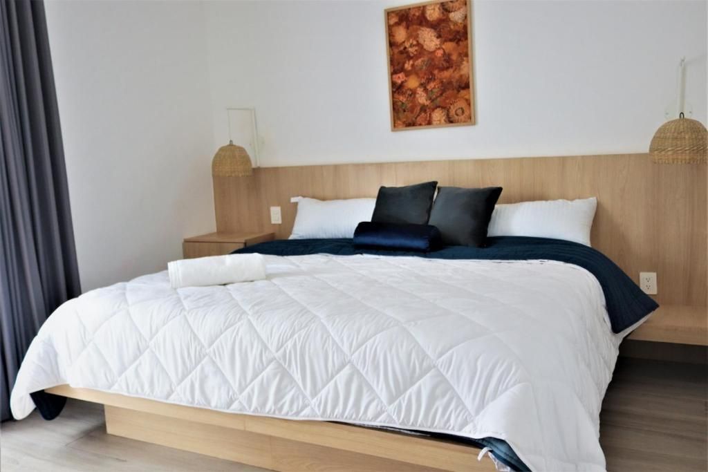 Una camera d'albergo con un letto, un comodino, una lampada a parete e un quadro.