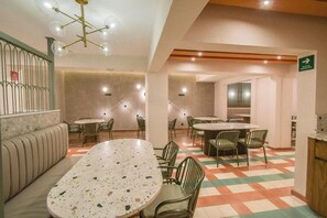 A hotel lobby with a large round table, several chairs, a sofa, and a staircase with a railing. - Expo Satelite Hotel and Suites (Guadalajara)