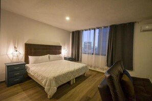 Una camera d'albergo con un letto, comodini, una sedia e una finestra con tende.