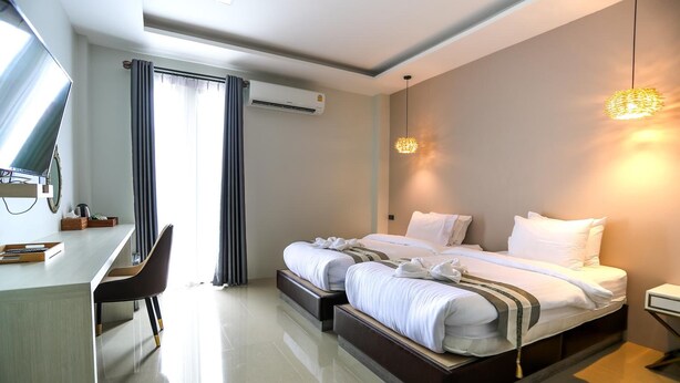 Quarto de hotel com cama, mesas de cabeceira, escrivaninha, cadeira e ar condicionado.