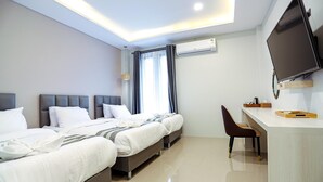 Quarto de hotel com duas camas, uma escrivaninha, uma cadeira, televisão de tela plana e ar condicionado.