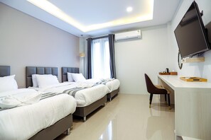 A hotel room with two beds, a desk, a chair, a flat-screen TV, and an air conditioning unit. - Worachat Boutique Hotel (Wang Thong)