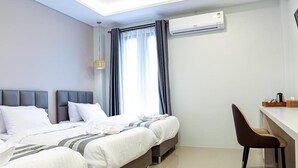 A modern hotel room with a large bed, a desk, and an air conditioning unit. - Worachat Boutique Hotel (Wang Thong)