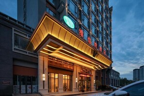 A hotel with a modern facade, large windows, and a prominent entrance with a curved overhang. - Vienna Hotel (Chengdu)