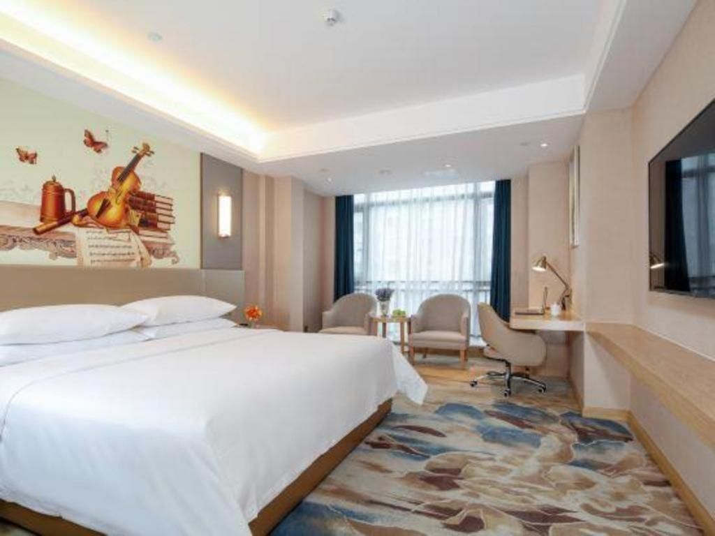 A hotel room with a bed, a desk, a chair, and a large window.