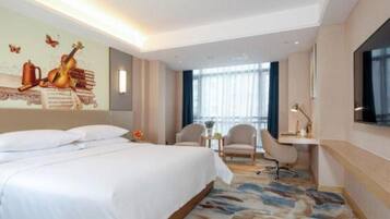 A hotel room with a bed, a desk, a chair, and a large window.