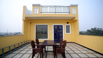 A yellow building with a balcony, a blue door, and a table with chairs.