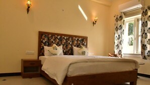 Ein Schlafzimmer mit einem hölzernen Bett, zwei Nachttischen, einem Beistelltisch und einem Fenster mit gemusterten Vorhängen.
