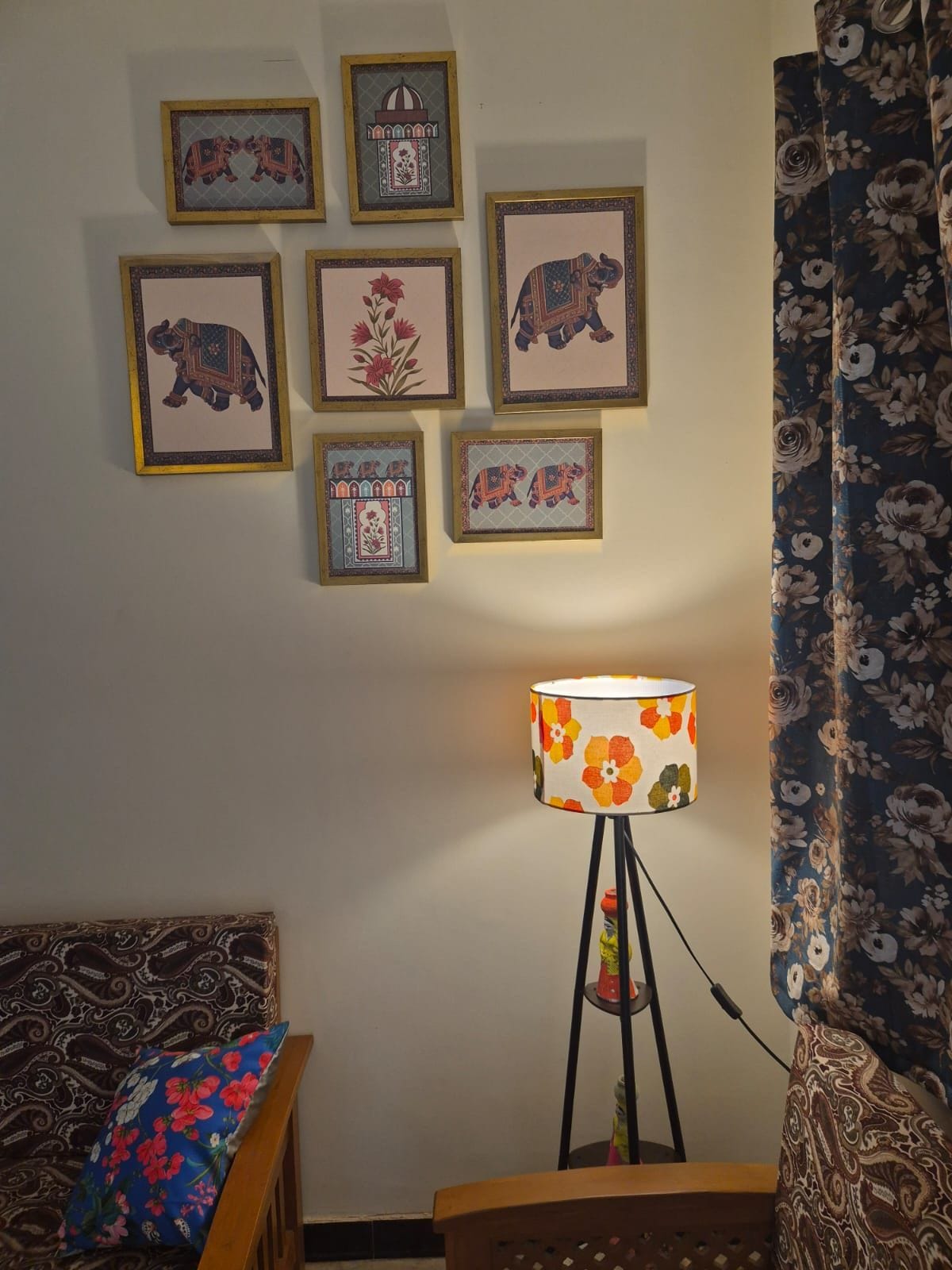 A room with a bed, a lamp, and framed artwork on the wall.
