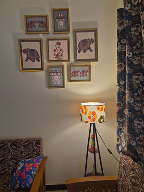 A room with a bed, a lamp, and framed artwork on the wall. - Arti's Homestay (Agra)