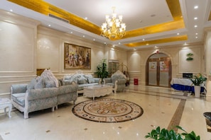 A spacious lobby with ornate furniture, a large chandelier, and a classic painting on the wall. - Vienna Hotel (Suzhou)