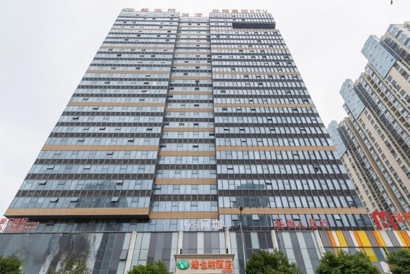 A high-rise building with multiple floors, featuring a modern architectural design with a grid of windows. - Vienna Hotel (Suzhou)