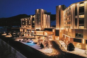 Un hôtel moderne doté d’une piscine, de plusieurs bâtiments et offrant une vue sur un paysage montagneux.