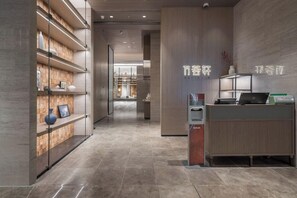 Un espace d’accueil avec un comptoir de réception en bois, un ordinateur et un panneau fixé au mur.