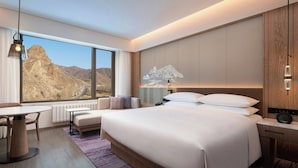 A hotel room with a large bed, a desk, and a view of mountains. - Courtyard By Marriott Chongli (Zhangjiakou)