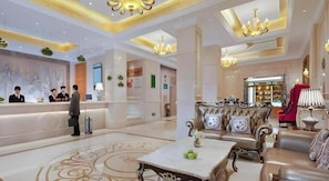 A hotel lobby with a reception desk, seating area, and a chandelier. - Vienna Hotel (Kunming)