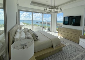 Ein modernes Schlafzimmer mit einem großen Bett, einem Fernseher und Meerblick.