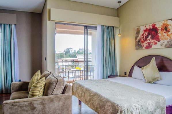 Habitació d'hotel amb llit, sofà i balcó amb taula i cadires.