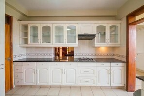 A kitchen with white cabinets, a black countertop, and a gas stove. - Kengen RBS Gardens Apartments (Nairobi)