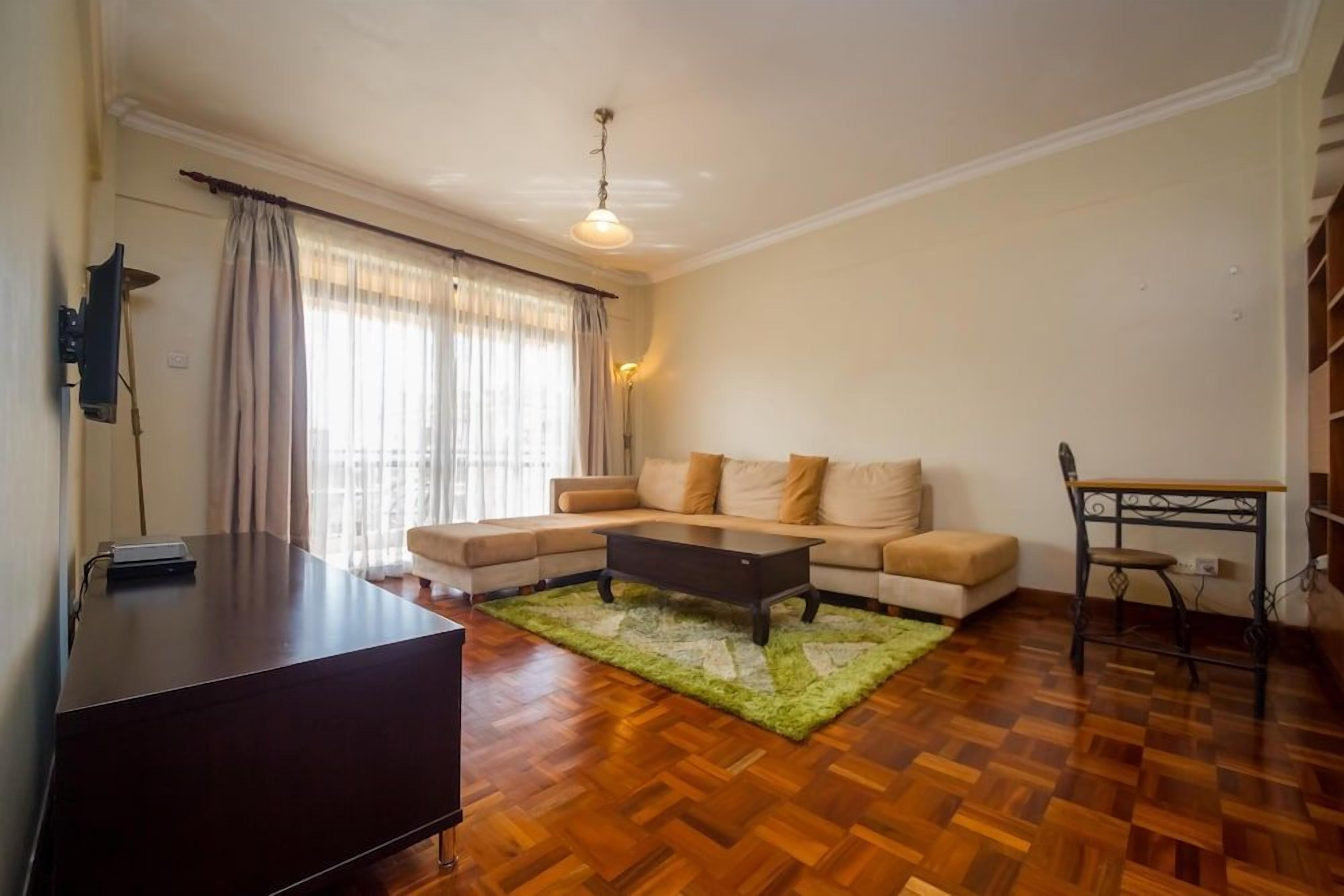 A living room with a sofa, a coffee table, a TV, and a dining table with chairs.