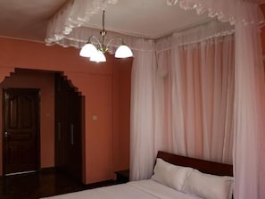A bedroom with a bed, a chandelier, and a staircase. - Kengen RBS Gardens Apartments (Nairobi)
