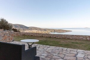 Un patio al aire libre con piso de piedra, una mesa redonda y mobiliario de mimbre.