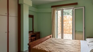 Un dormitorio con cama, cómoda, espejo y puerta corrediza de vidrio que da a un espacio exterior.