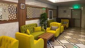 A lobby with yellow sofas, a wooden coffee table, and a patterned floor. - Salsbil Almasi (Madinah)