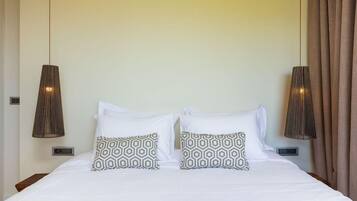 A hotel room with a bed, two bedside lamps, and a window with curtains.