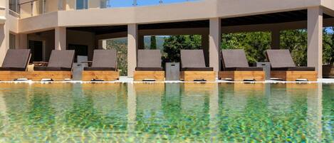 Un área de piscina con sillones reclinables y una terraza techada.