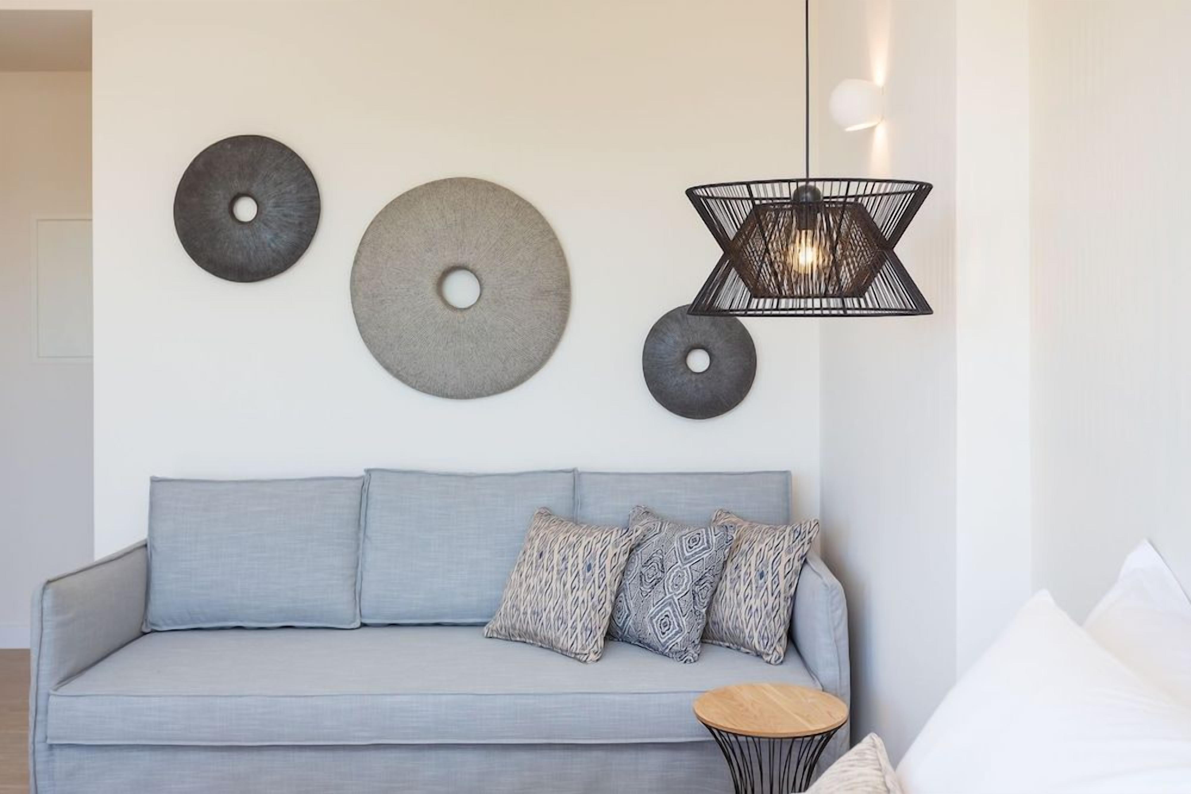 A modern living room with a grey sofa, patterned cushions, and a small round table.