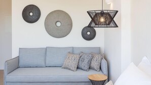 Uma sala de estar moderna com um sofá cinzento, almofadas estampadas e uma mesa redonda.