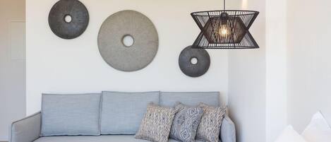 A modern living room with a grey sofa, patterned cushions, and a small round table.
