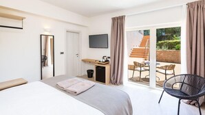 Quarto de hotel com cama, escrivaninha, televisão de tela plana, uma cadeira e vista para o pátio externo.