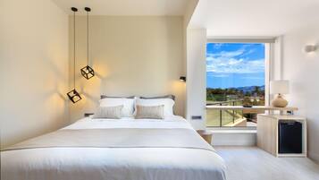 A modern bedroom with a large bed, a view of the outdoors, and a small kitchenette area.