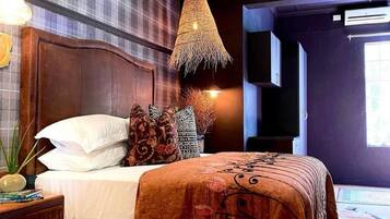 A bedroom with a large bed, a wooden headboard, a woven lamp, and a patterned rug.
