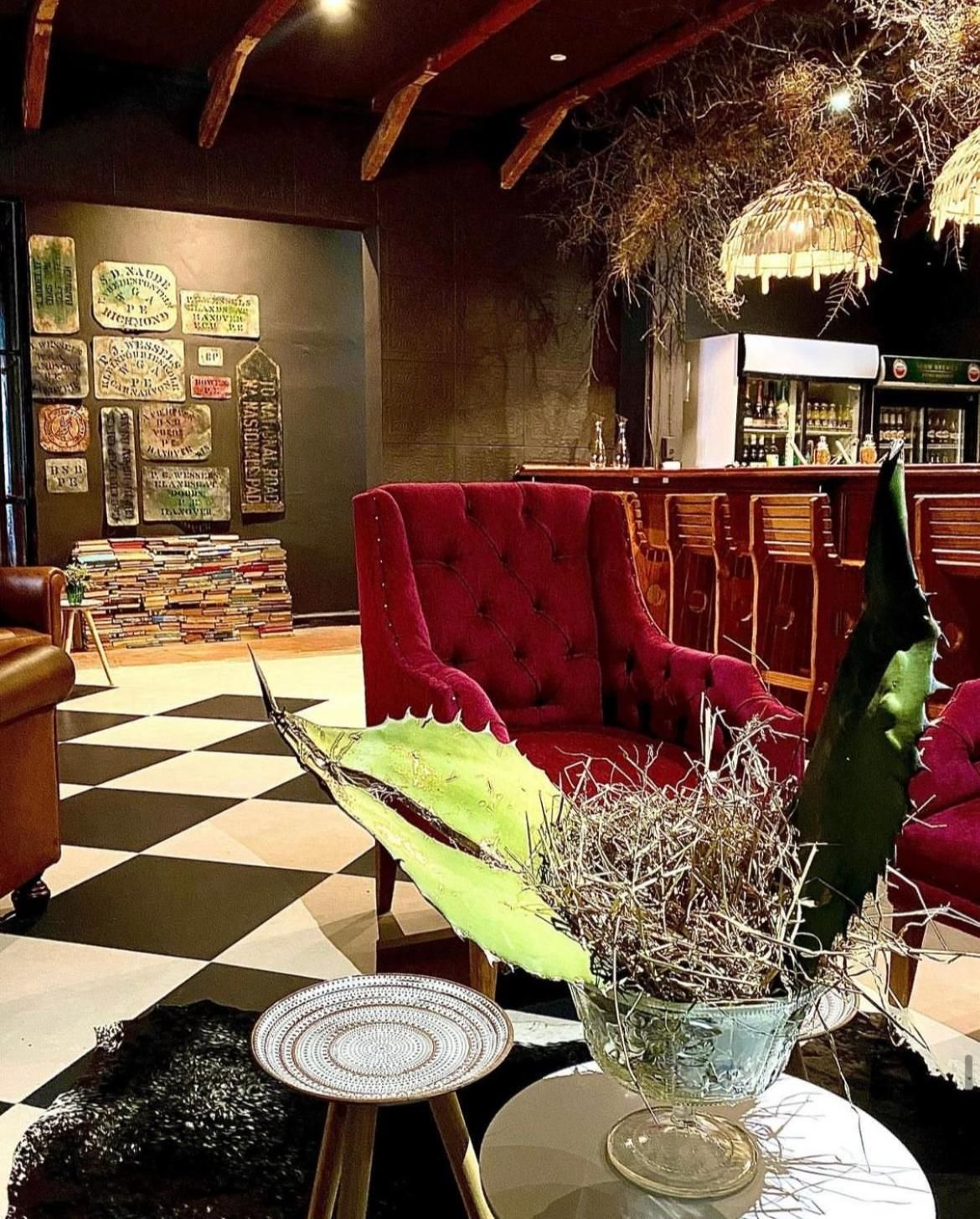 A room with a red sofa, a table with a cactus, and a checkered floor.