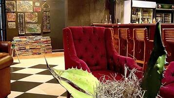 A room with a red sofa, a table with a cactus, and a checkered floor.
